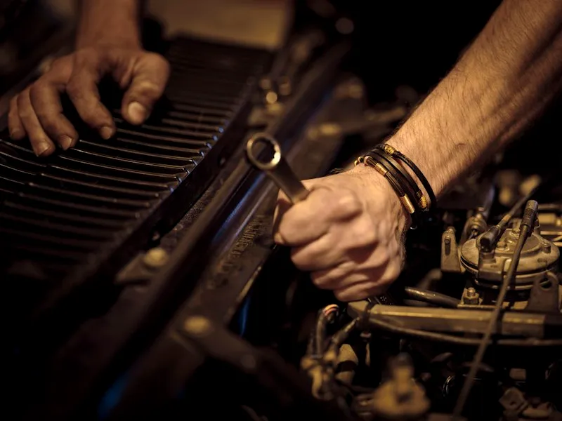 Mechanik dokręca element silnika kluczem