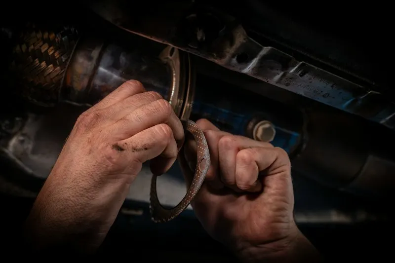 Ręce mechanika zakładające uszczelkę układu wydechowego
